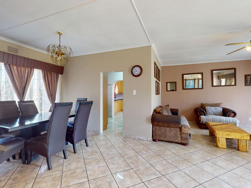 Spacious open-plan living and dining area featuring tiled flooring, a ceiling fan, and an archway leading to the kitchen.