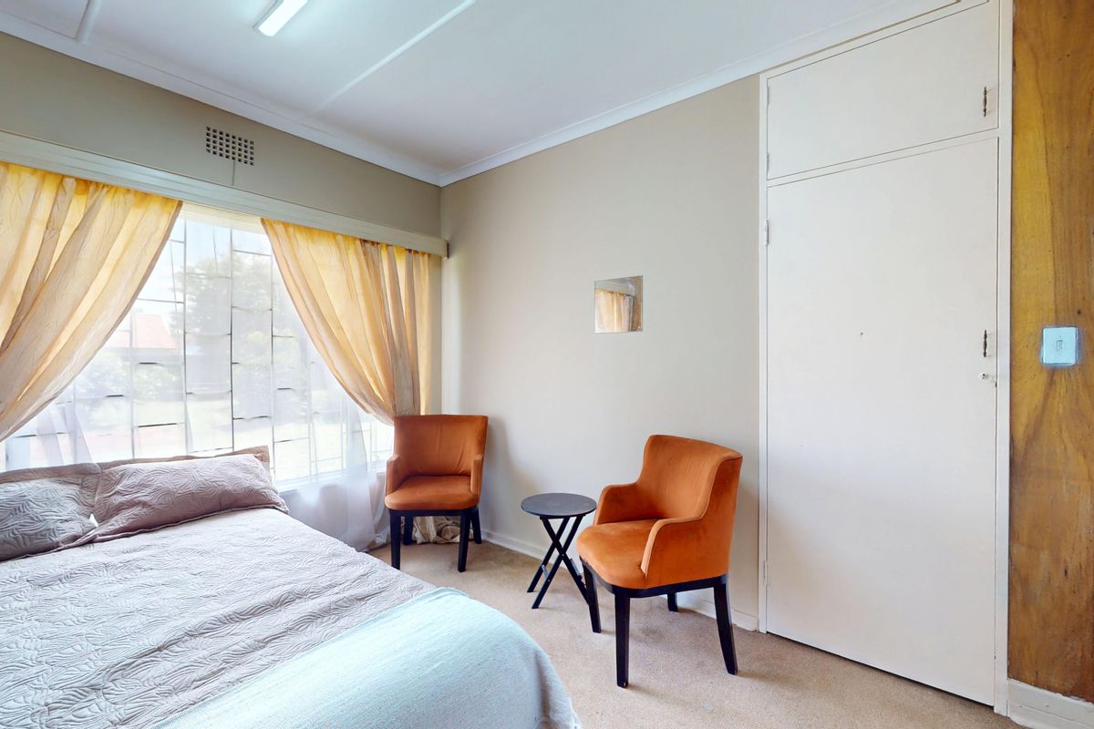 A bedroom featuring a built-in cupboard, large window with natural light, and carpeted flooring.