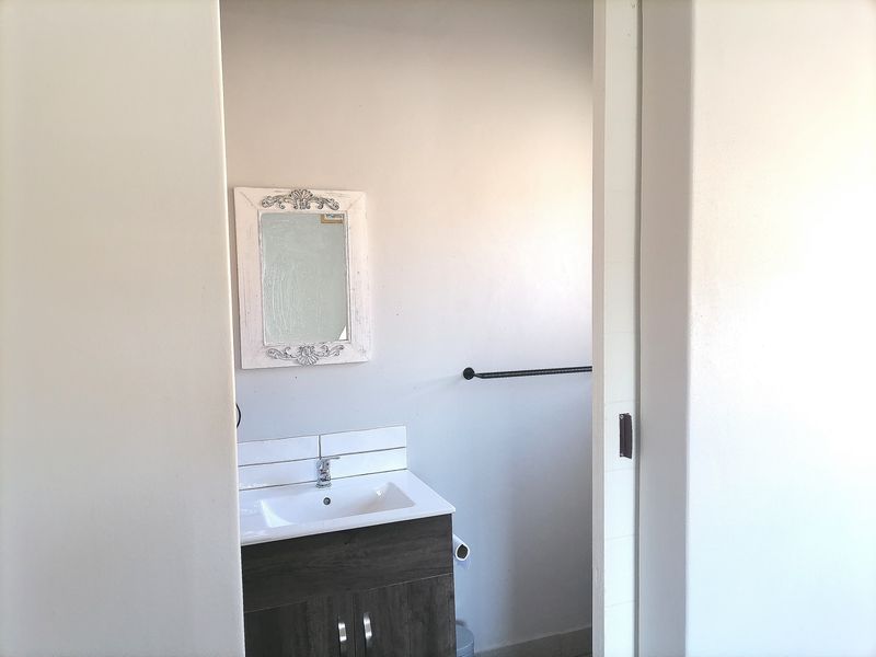 A clean and functional bathroom featuring a modern vanity cabinet with a ceramic basin, chrome mixer tap, and a wall-mounted towel rail.
