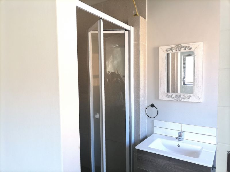 A functional bathroom featuring a shower enclosure, a modern vanity basin with a tiled splashback, and a wall-mounted towel ring.