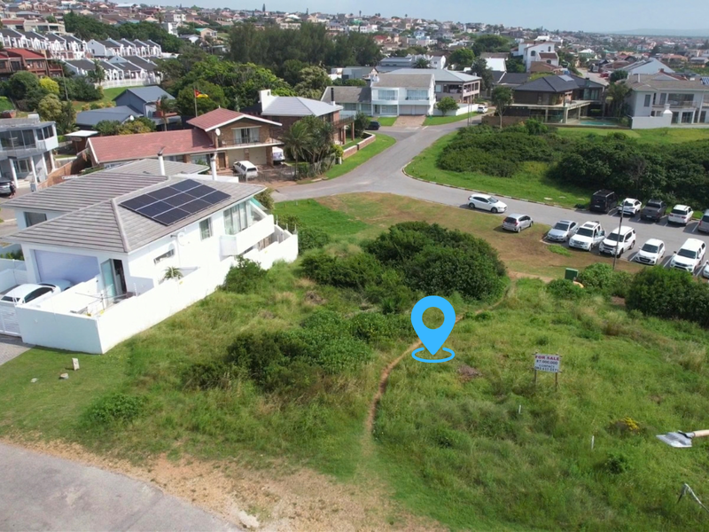 Aerial view of a vacant residential plot situated in a developed coastal neighborhood, offering proximity to existing homes and local street infrastructure.