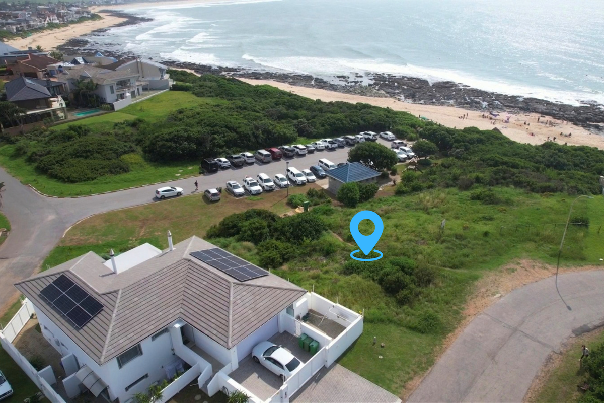 Aerial view of a residential vacant land plot situated in a coastal neighborhood, featuring proximity to the beach and existing surrounding infrastructure.