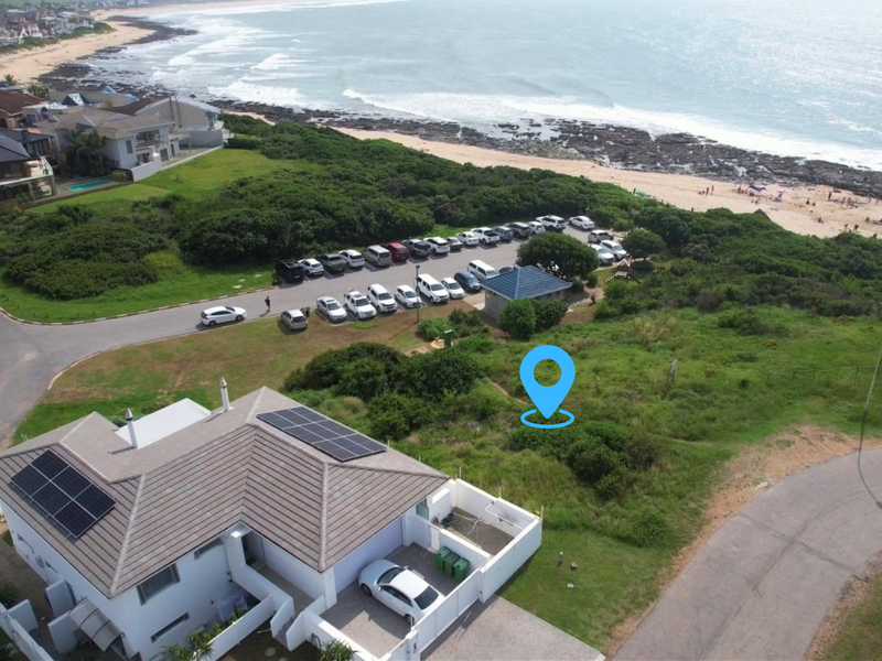 Aerial view of a residential vacant land plot situated in a coastal neighborhood, featuring proximity to the beach and existing surrounding infrastructure.
