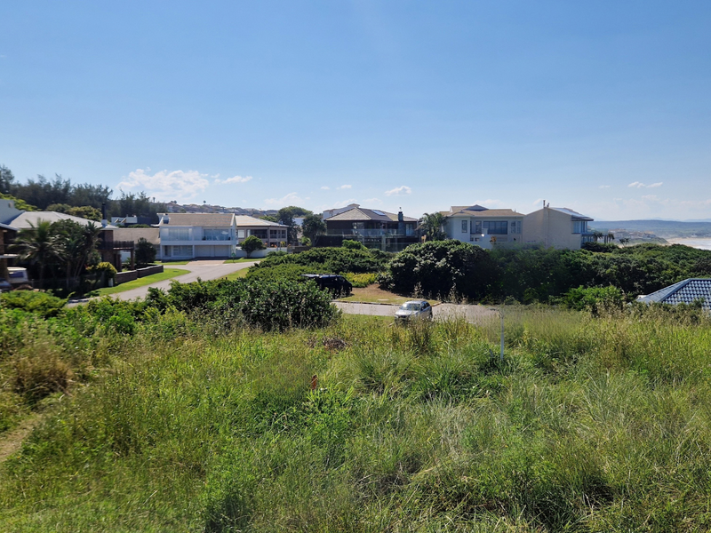 A view of a vacant residential plot situated in a coastal neighborhood with surrounding homes and natural vegetation.