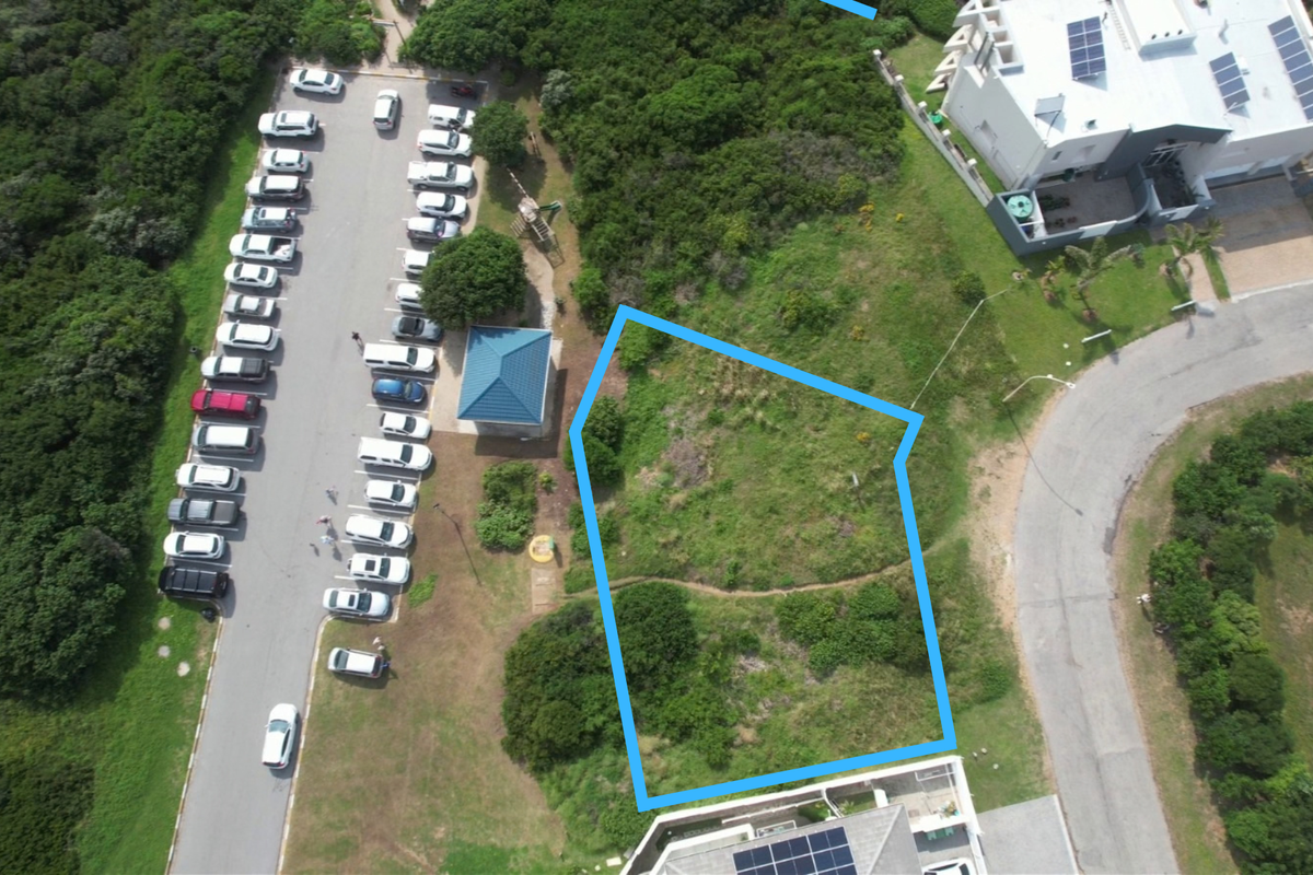 Aerial view of a vacant residential plot with clear boundary markings, situated in a developed coastal neighborhood.