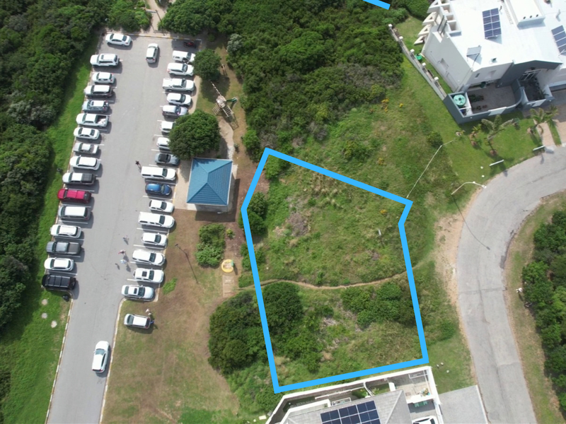 Aerial view of a vacant residential plot with clear boundary markings, situated in a developed coastal neighborhood.