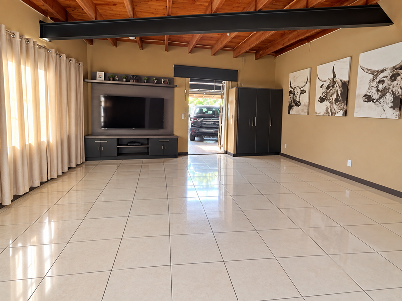 Spacious living area featuring high exposed timber beam ceilings, polished tile flooring, and custom built-in cabinetry for media and storage.