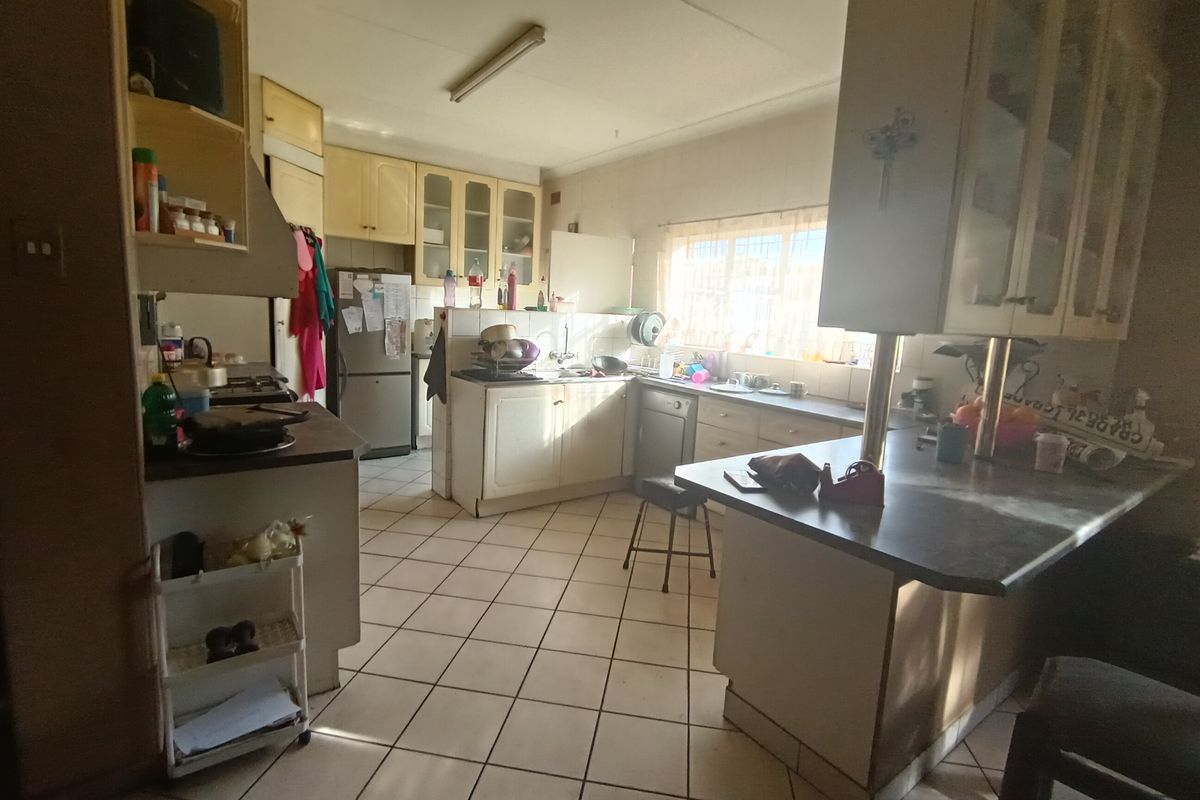 A functional kitchen featuring built-in cabinetry, laminate countertops, a breakfast bar, and ceramic tile flooring, offering potential for modernization and aesthetic updates.