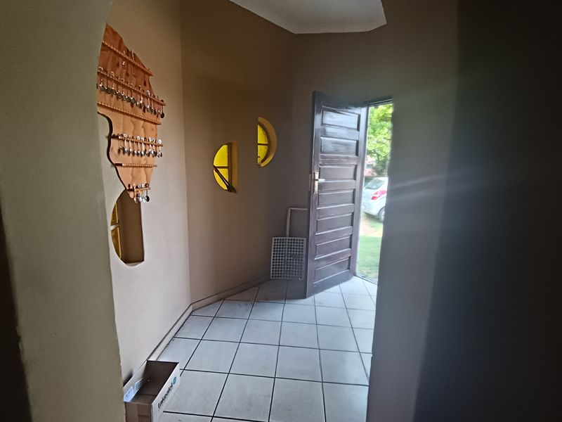 An entrance hall featuring tiled flooring, unique circular windows, and an arched entryway leading to a solid timber front door.