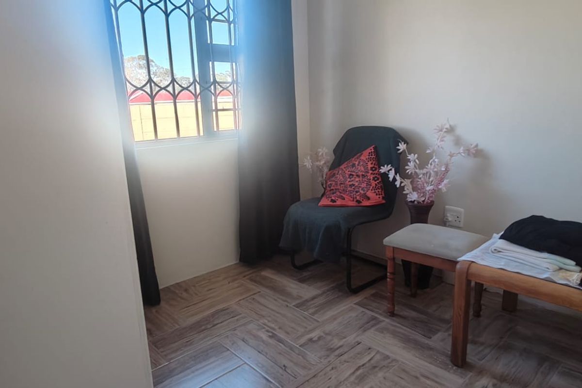 A bedroom featuring herringbone-patterned tiled flooring and a window fitted with a security gate, offering a functional and neutral living space.