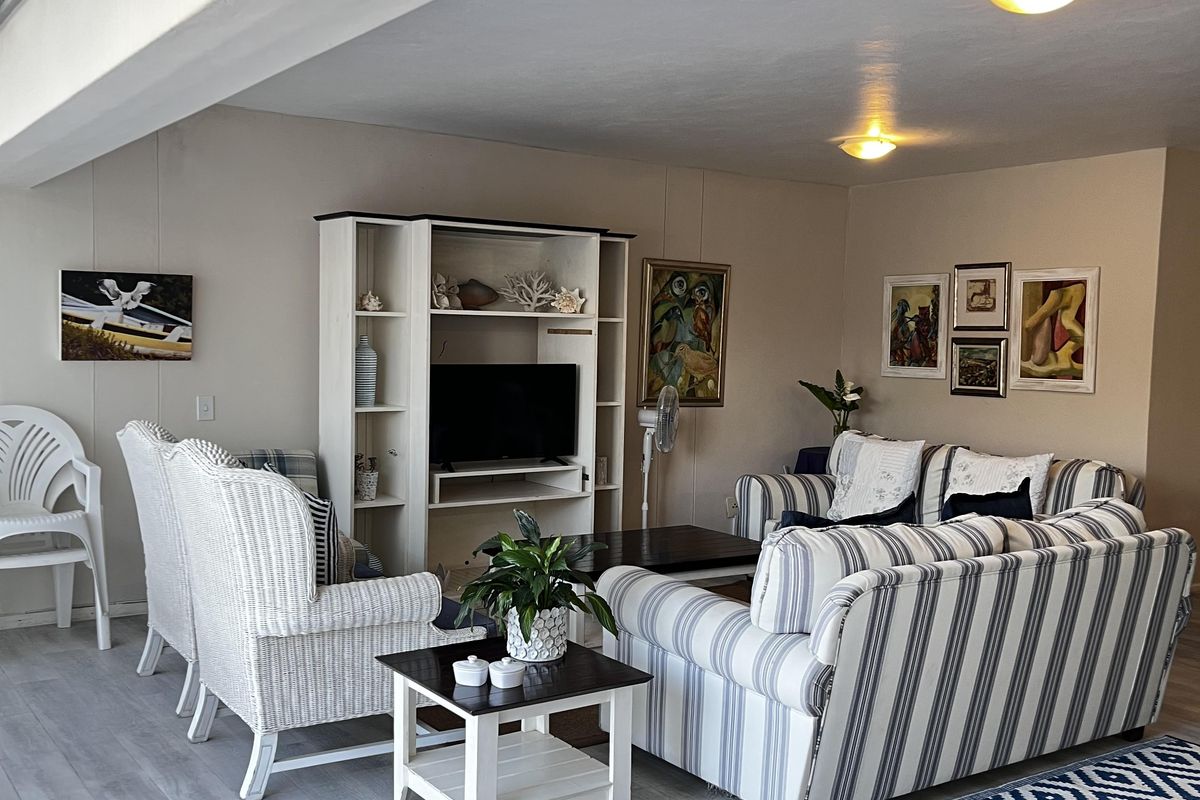 A bright and spacious living room featuring modern laminate flooring, recessed lighting, and a large skylight, creating an airy and inviting atmosphere.