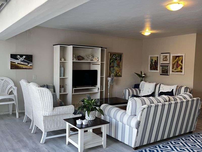 A bright and spacious living room featuring modern laminate flooring, recessed lighting, and a large skylight, creating an airy and inviting atmosphere.