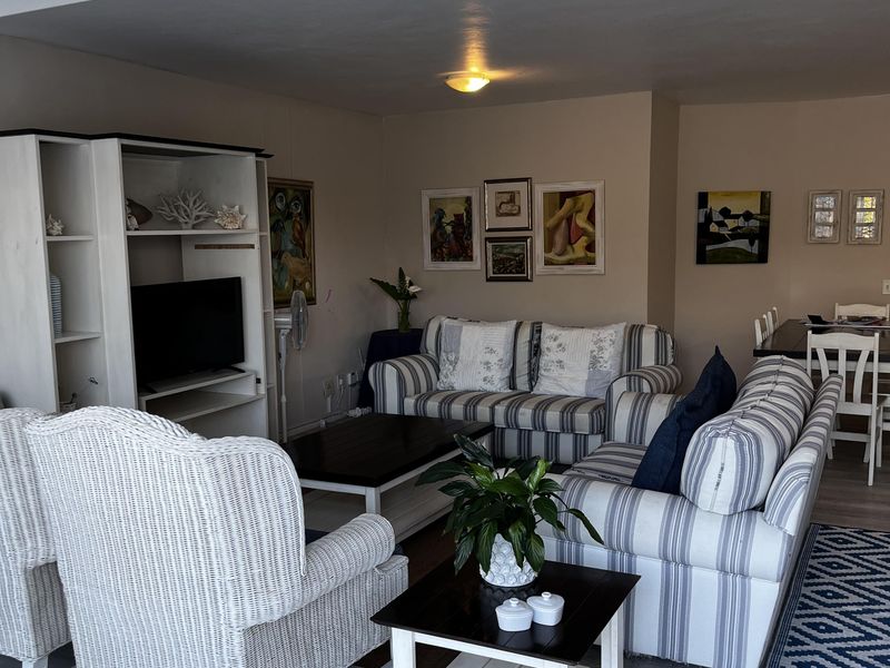 An open-plan living and dining area featuring light-toned laminate flooring and flush-mount ceiling lighting, providing a functional and connected space for relaxation and meals.