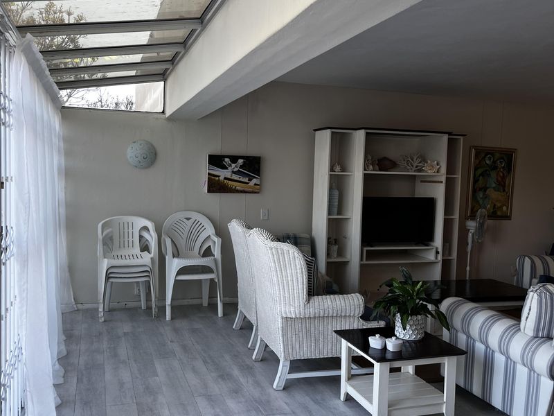 Enclosed patio area featuring a glass roof and light-toned laminate flooring, providing a bright and versatile transition space.