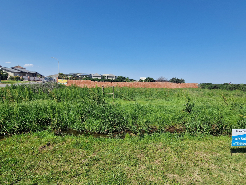 A vacant residential plot featuring a grassed surface and a brick boundary wall, situated in a developed neighborhood.