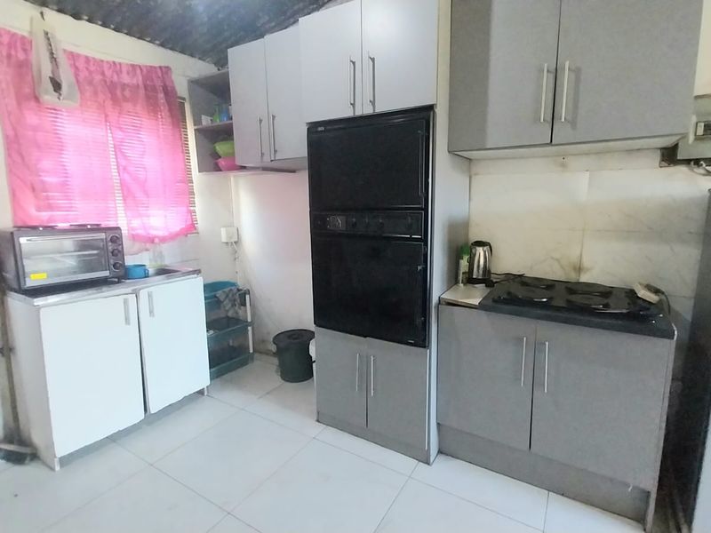 A functional kitchen featuring built-in cabinetry, a built-in oven, and a hob, with tiled flooring and basic utility fixtures.