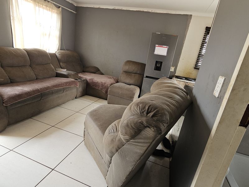 A living room area featuring tiled flooring and grey walls in need of maintenance and cosmetic updates.