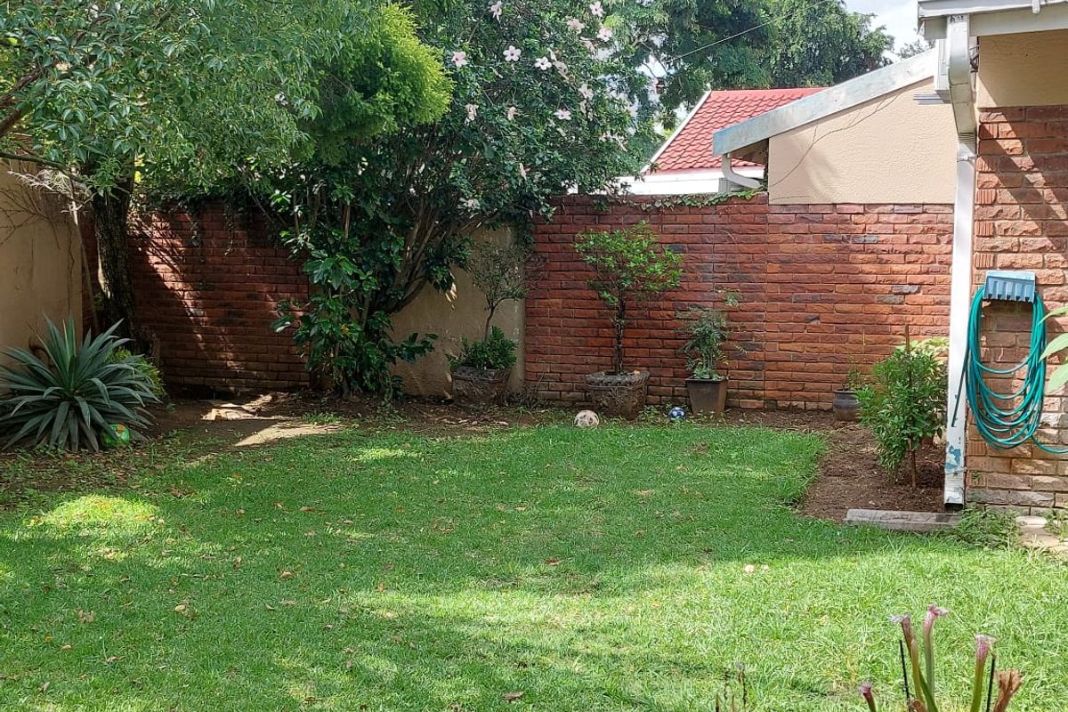 A private rear garden area featuring a well-maintained lawn and a solid brick boundary wall, providing a secure and pleasant outdoor space.