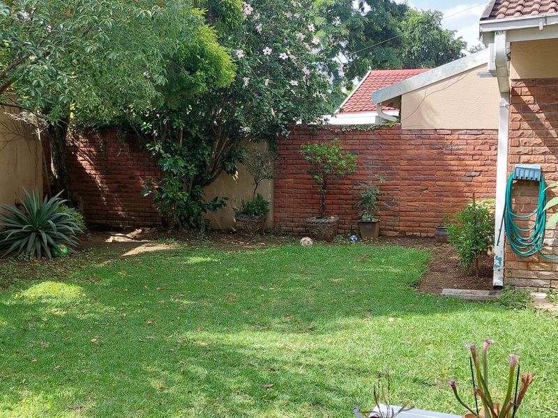 A private rear garden area featuring a well-maintained lawn and a solid brick boundary wall, providing a secure and pleasant outdoor space.