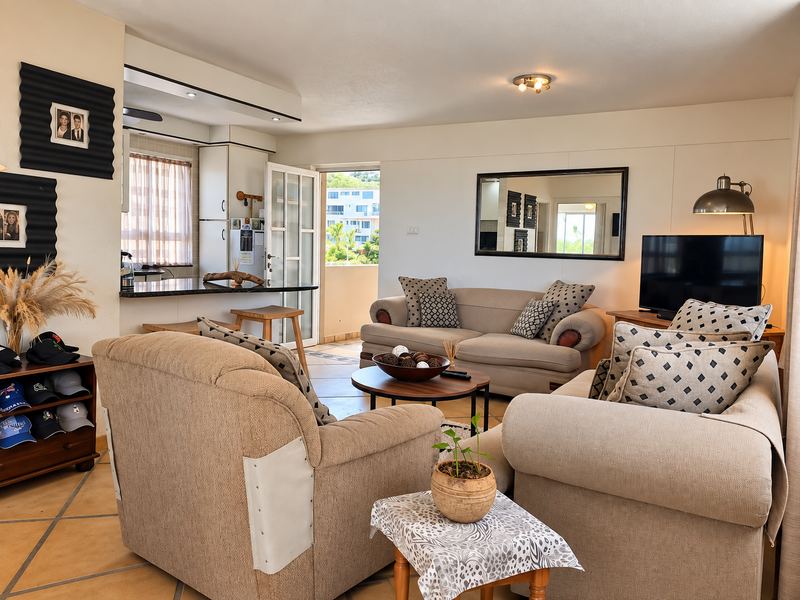 Open plan living area featuring tiled flooring, a breakfast bar connecting to the kitchen, and direct access to an outdoor balcony.
