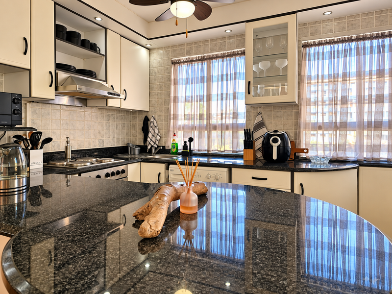 A well-maintained kitchen featuring dark granite countertops, cream cabinetry, tiled backsplash, and integrated appliances, offering a functional and classic cooking space.