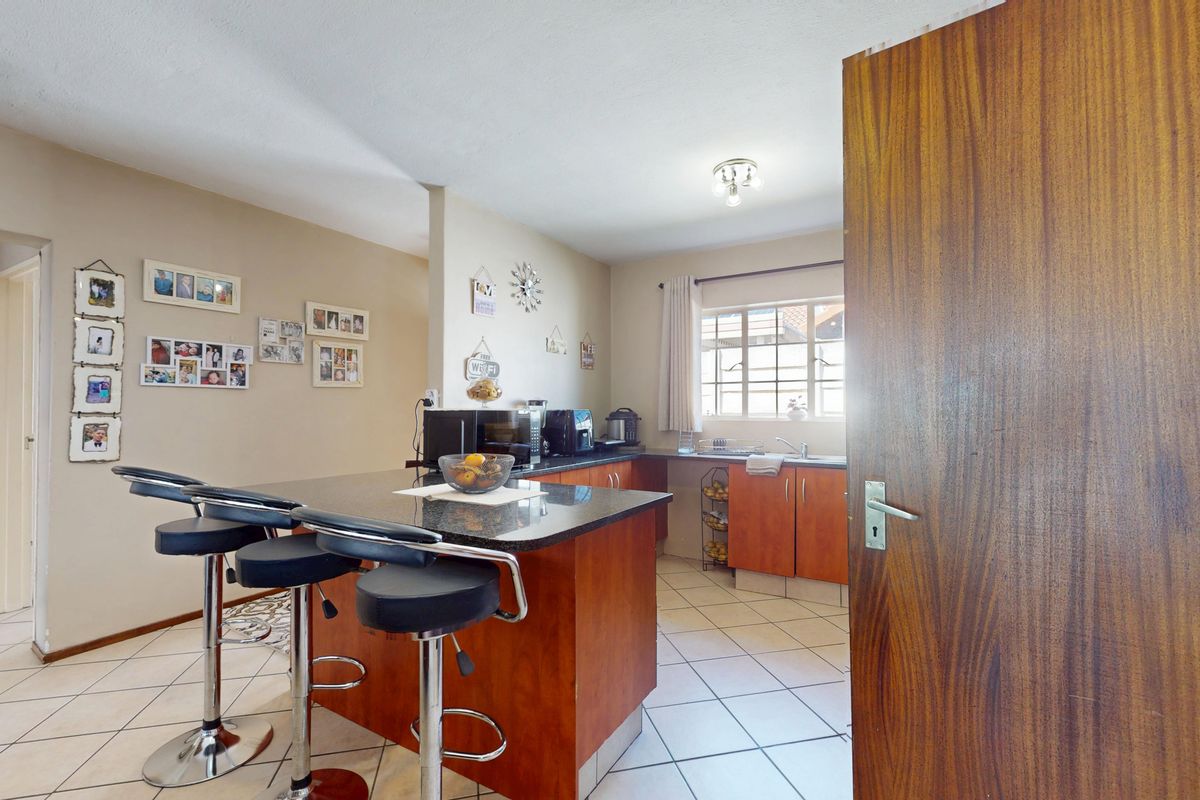 A functional kitchen featuring wooden cabinetry, granite countertops, a breakfast bar, and tiled flooring, offering a practical layout for daily meal preparation.