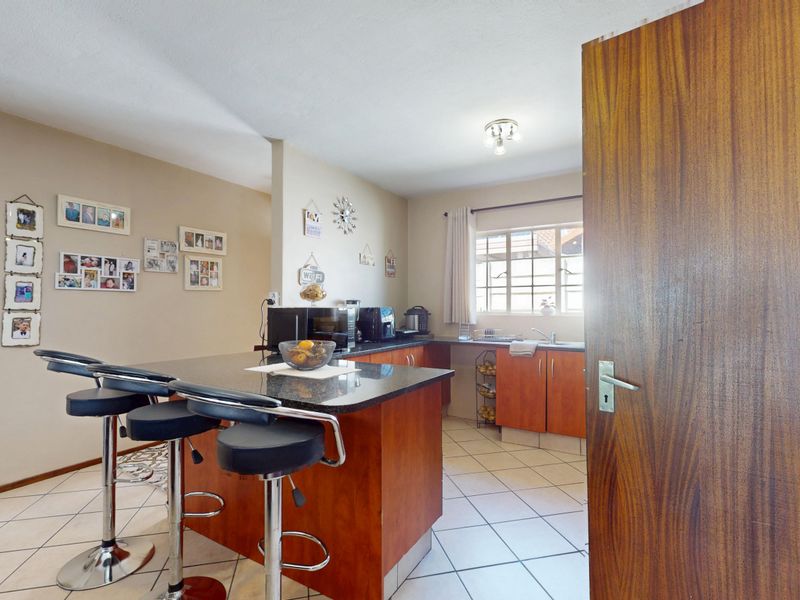 A functional kitchen featuring wooden cabinetry, granite countertops, a breakfast bar, and tiled flooring, offering a practical layout for daily meal preparation.