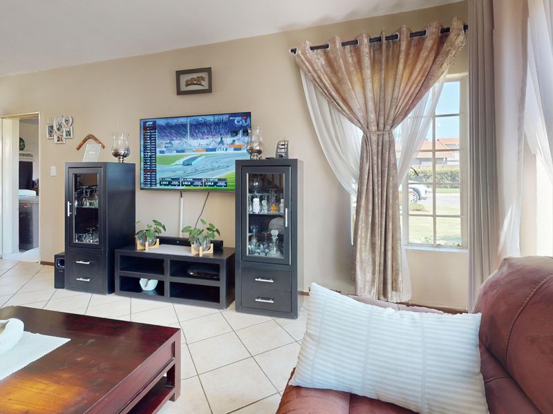 A comfortable living room featuring tiled flooring and natural light from a side window, providing a functional space for relaxation.