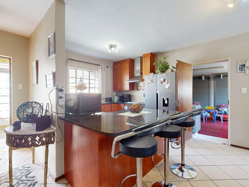 Open plan kitchen featuring granite countertops, wooden cabinetry, and a breakfast bar, seamlessly connecting to the living area and adjacent utility space.