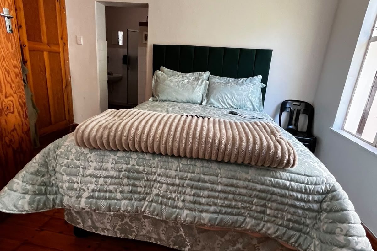 A bedroom featuring original timber flooring, a built-in wooden wardrobe, and direct access to an en-suite bathroom.