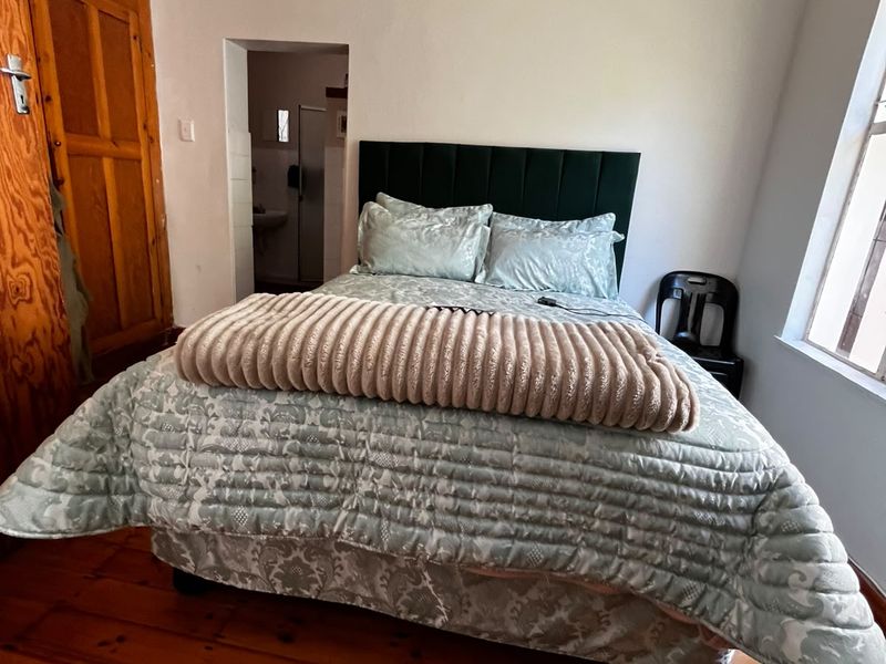 A bedroom featuring original timber flooring, a built-in wooden wardrobe, and direct access to an en-suite bathroom.
