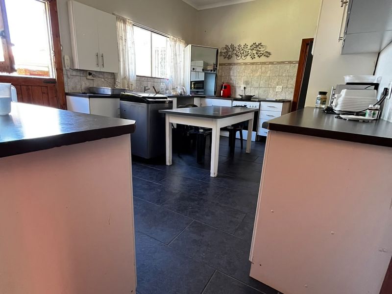 A functional kitchen featuring tiled flooring, built-in cabinetry, and laminate countertops, offering a practical layout with potential for modern updates.
