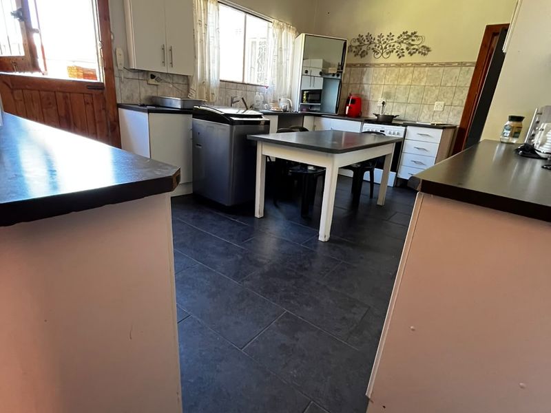A functional kitchen featuring dark tiled flooring, built-in cabinetry with laminate countertops, and a tiled backsplash, offering a practical layout for daily use.