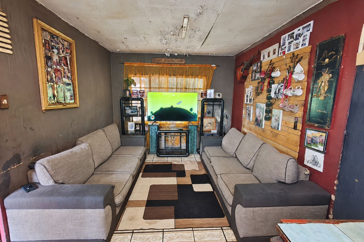 A living room featuring tiled flooring and timber wall accents, currently requiring significant ceiling and wall repairs to restore the space.