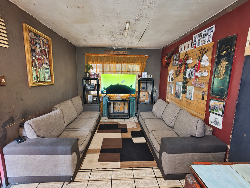 A living room featuring tiled flooring and timber wall accents, currently requiring significant ceiling and wall repairs to restore the space.