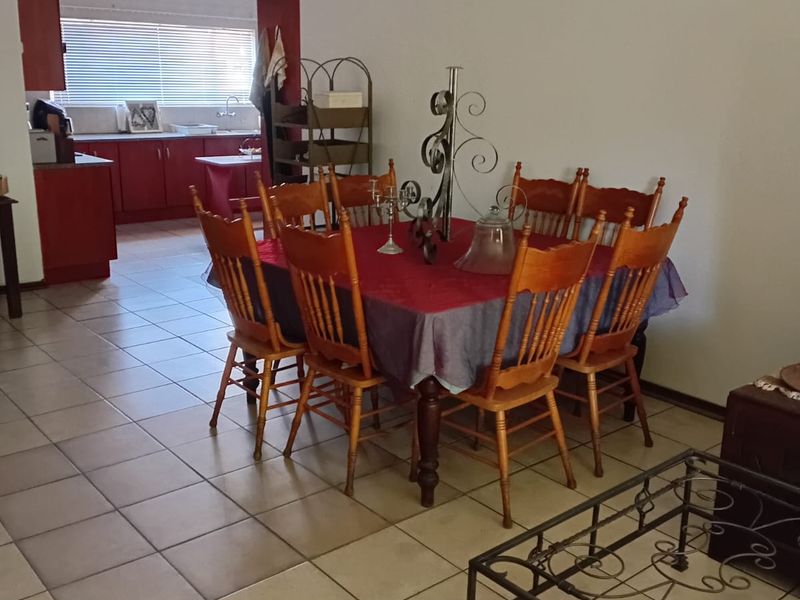Open plan dining area flowing into a functional kitchen with tiled flooring and cabinetry.