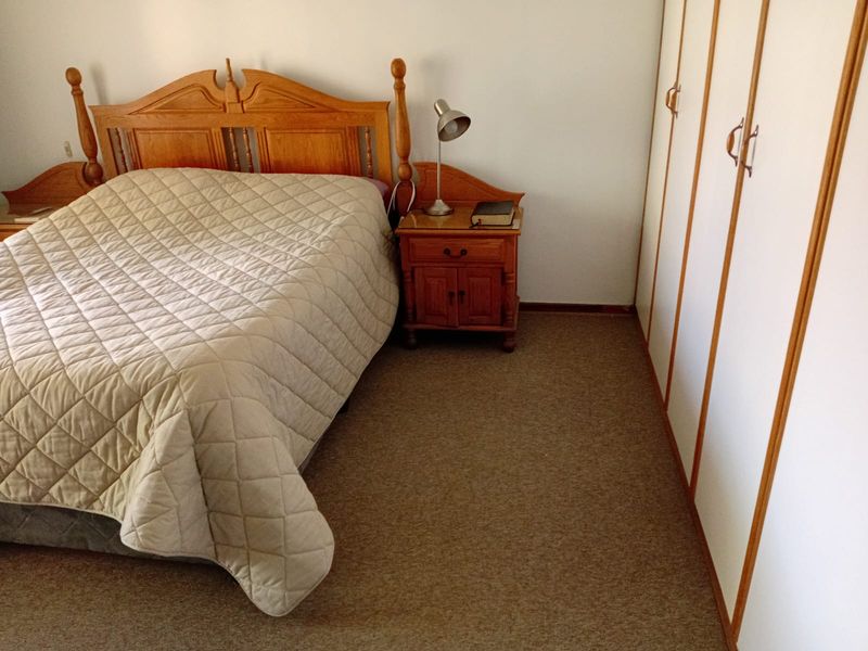 A bedroom featuring neutral carpeted flooring and built-in cupboards, offering a functional and well-maintained space.