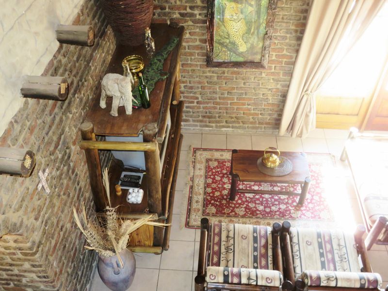 A living area featuring rustic exposed brick walls, tiled flooring, and decorative timber ceiling beams, offering a warm and textured interior aesthetic.