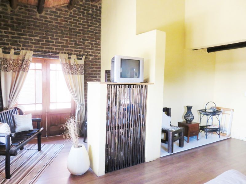 Living area featuring exposed brickwork, timber double doors, and high ceilings with exposed wooden beams, creating a rustic and character-filled space.