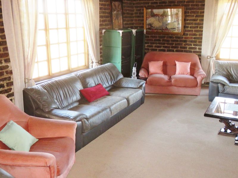 A living room featuring exposed brick walls, large timber-framed windows, and neutral carpeting, offering a classic aesthetic with potential for modern updates.
