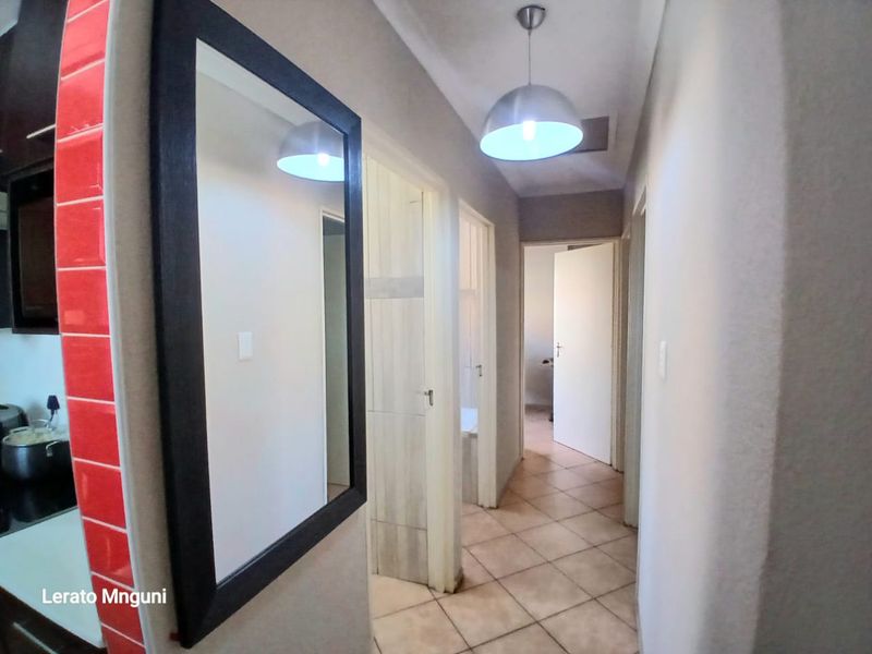 A functional hallway featuring tiled flooring and pendant lighting, providing access to multiple rooms within the home.