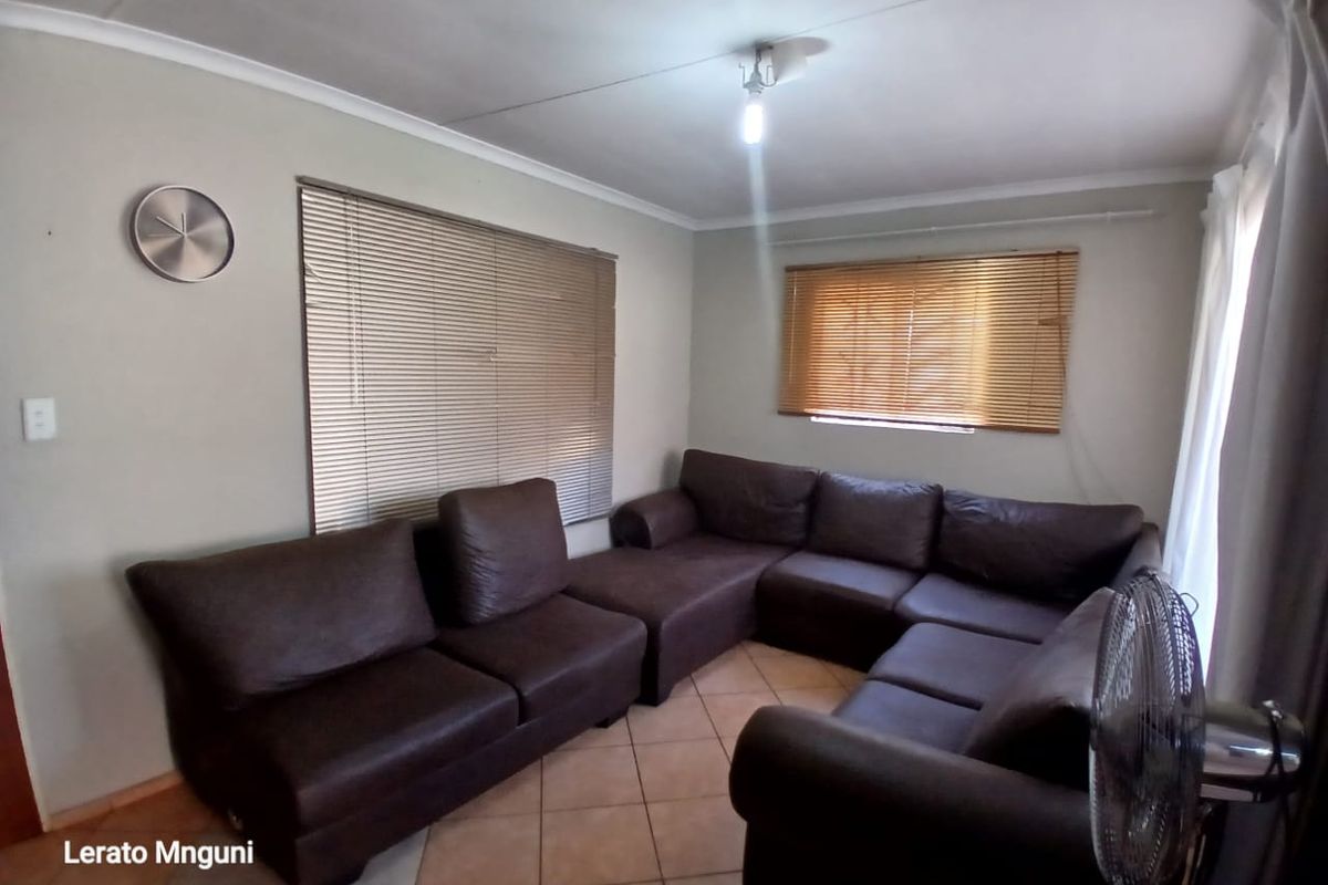 A living room featuring tiled flooring and venetian blinds, providing a functional and neutral space for relaxation.