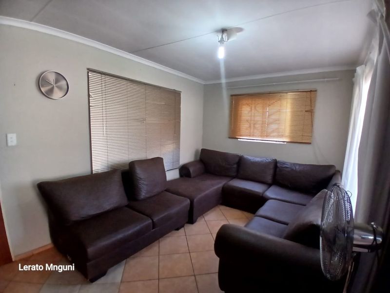 A living room featuring tiled flooring and venetian blinds, providing a functional and neutral space for relaxation.