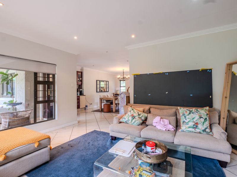 Spacious open-plan living and dining area featuring tiled floors, recessed lighting, and seamless access to an outdoor patio through large sliding glass doors.
