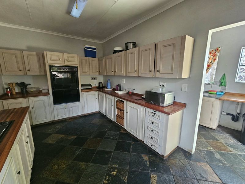 A functional kitchen featuring traditional cabinetry, wooden countertops, and durable slate tile flooring, offering a classic layout with ample storage space.