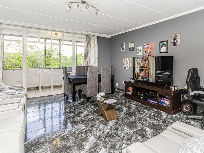 Open plan living and dining area featuring tiled flooring and large sliding glass doors leading to an attached balcony.