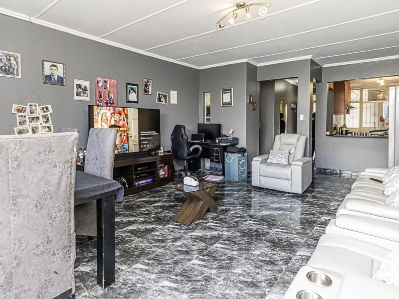 Open-plan living and dining area featuring marble-effect tiled flooring, neutral grey walls, and a convenient pass-through window connecting to the kitchen.
