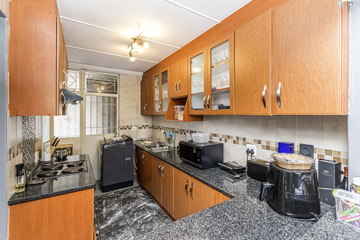 A functional kitchen featuring wooden cabinetry, granite countertops, a tiled backsplash, and integrated cooking appliances, offering a practical layout for daily meal preparation.