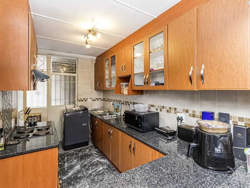 A functional kitchen featuring wooden cabinetry, granite countertops, a tiled backsplash, and integrated cooking appliances, offering a practical layout for daily meal preparation.