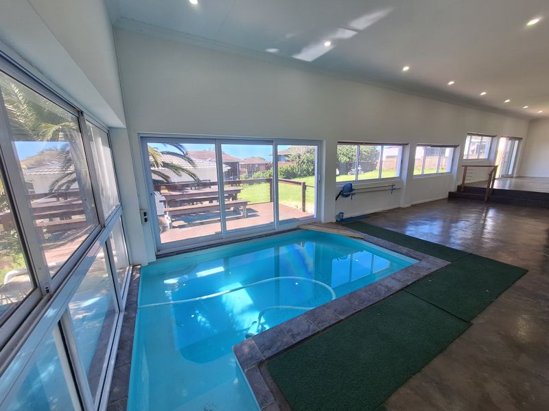 Indoor swimming pool area featuring large sliding glass doors, recessed lighting, and direct access to an outdoor deck.
